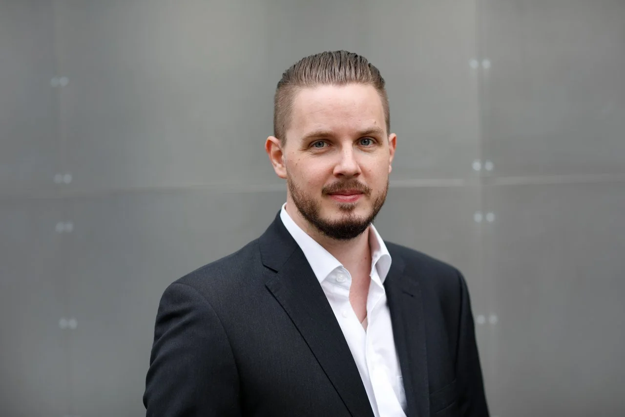 Darwin Droll in a dark suit and white shirt